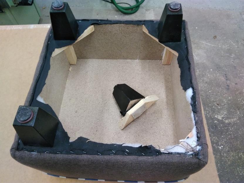 Unterseite eines Polstermöbels Unterseite eines gepolsterten Möbelstücks mit Holzrahmen und vier Füßen, einer davon gebrochen und gestützt.