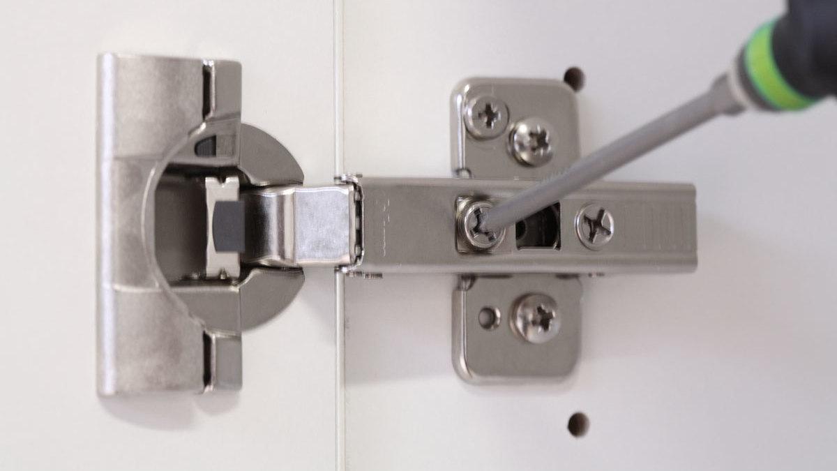 Detailaufnahme eines nachjustierbaren Türscharniers Detailaufnahme eines mit Schraubendreher nachjustierbaren Türscharniers