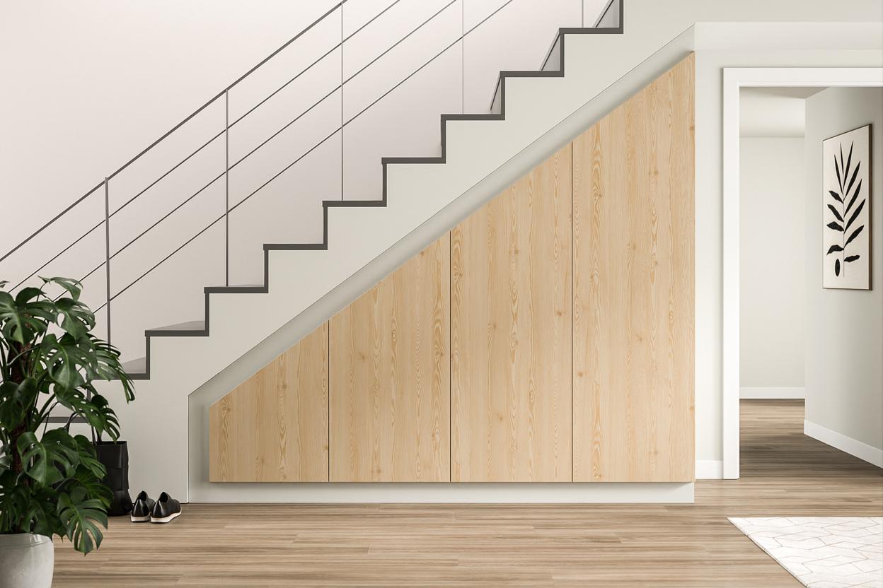 Maßgeschneiderter Schrank im Eingansbereich. Ein großer, an die Treppe angepasster Schrank nach Maß mit heller Holzoptik verleiht dem Eingangsbereich ein organisches und funktionales Design.