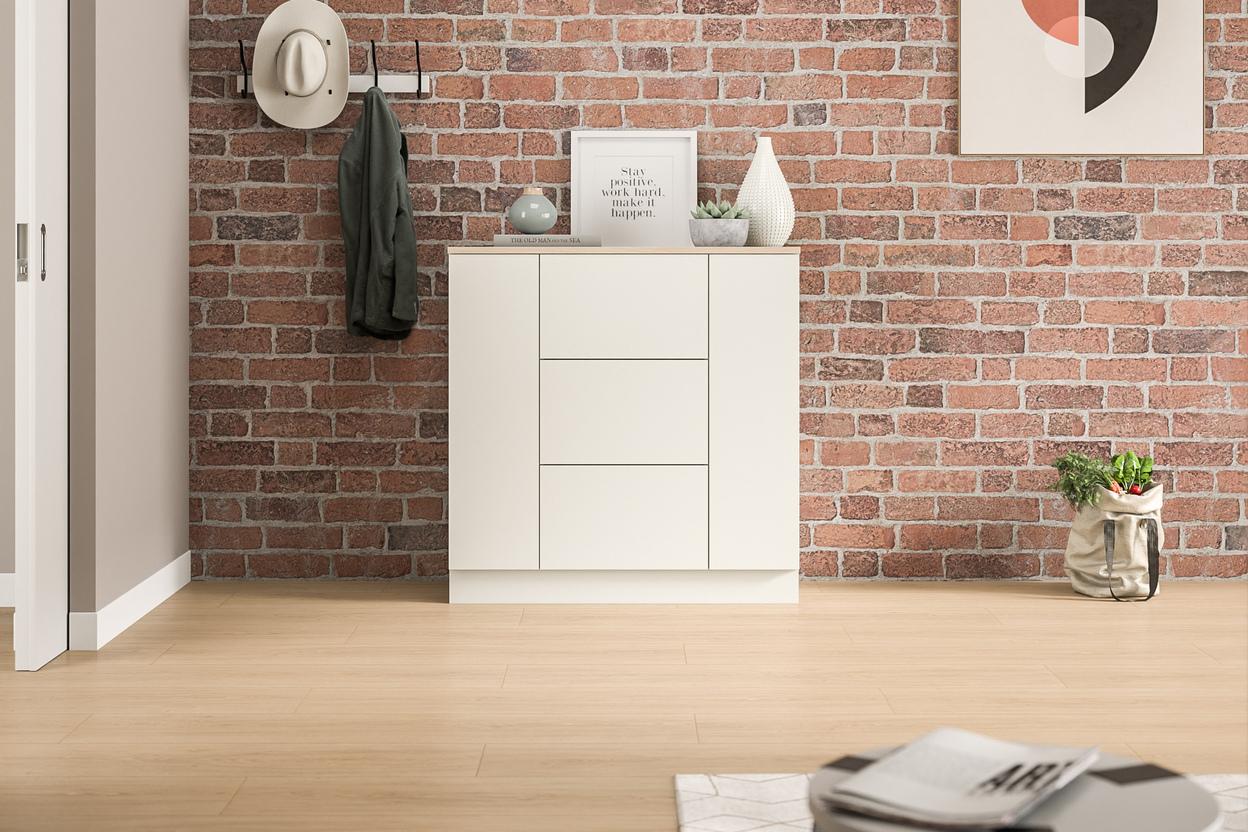 Moderne Kommode nach Maß vor einer Backsteinwand im Eingangsbereich. Eine schlichte, weiße Kommode nach Maß, die sich gegen eine rustikale Backsteinwand abhebt, bietet Stauraum und eine stilvolle Ablagefläche im Eingangsbereich.