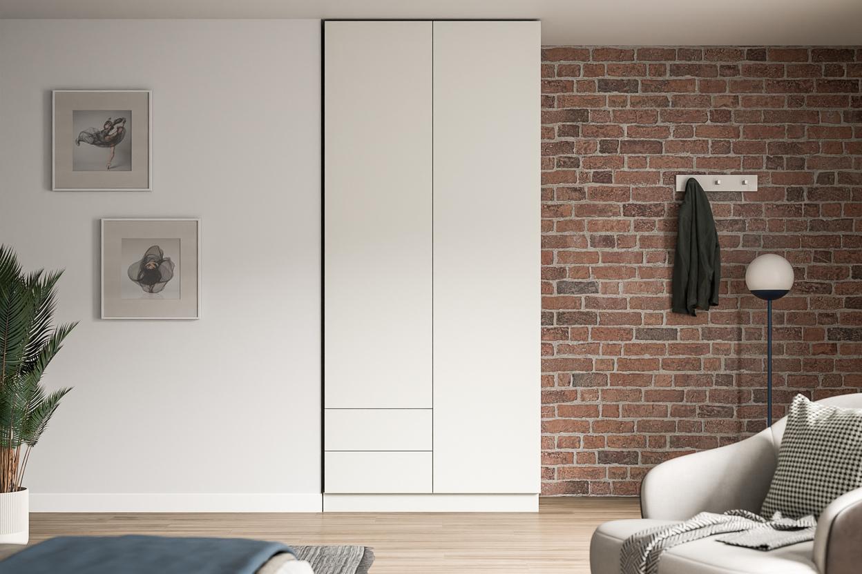 Eleganter Schrank nach Maß in modernem Wohnambiente Großer, maßgeschneiderter weißer Schrank im Kontrast zu einer Ziegelwand, neben Kunstwerken und einer stilvollen Stehlampe.